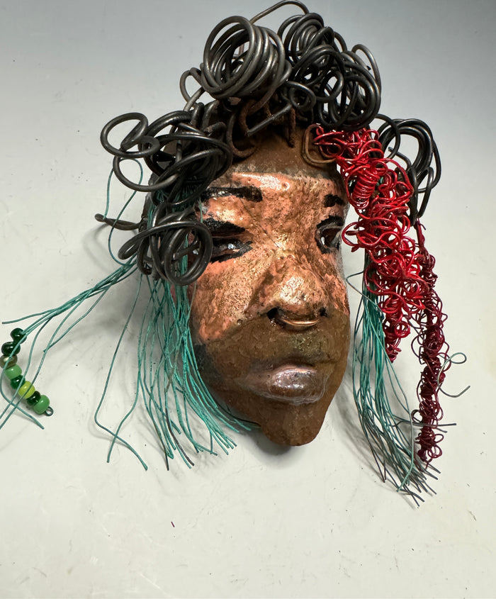 Dakari is an eye-catching two tone tribal raku mask, measuring 4 x 7" and weighing 6 oz. This mask is finished with a stunning blue and red hair. Dakari also features a copper nose ring. Shadowbox is not included.