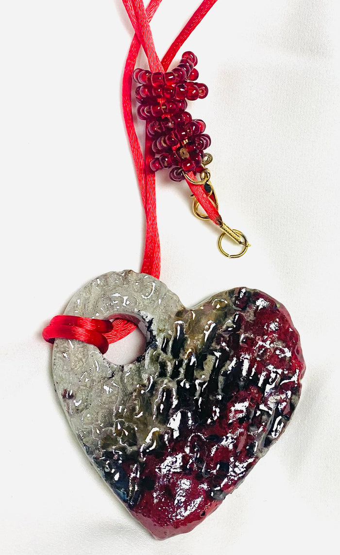Have A Heart ! Each heart pendant is handmade with love! It is 3"x 3" and weighs approx. 3ozs. This pendant has a copper gold metallic raku glazes that renders a unique translucent patina. The heart has a textured pattern . It holds a spiral of red mini beads on a spiral copper wire. This pendant has a nice 12" red suede cord!