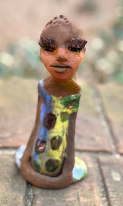 Adisa stands 7' x 4"x 2" and weighs 10.3 ozs. She has bright  dark eyes and a nice honey two tone brown complexion Her long trademark arms rest at her side. Adisa dress is a loving glossy blue and yellow mix with copper flashes.