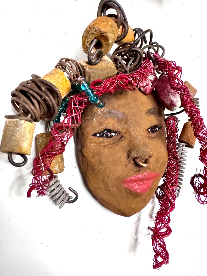 At 5" x 6" in size, Ola makes a stunning addition to walls, trees, and shadow boxes. His signature red braided hair is ornamented with handcrafted Raku beads, while his skin has a warm honey brown hue. Each piece is equipped with over 20 feet of top-notch 16 & 24-gauge wire in the hair. This fashionable sculpture will bring a modern flair to any room - simply place it in a shadow box and enjoy!