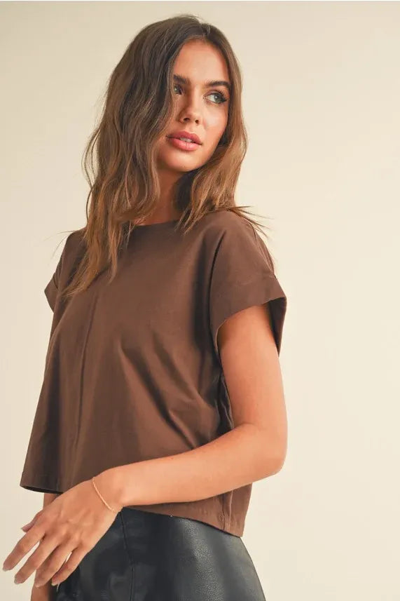 Woman modeling a round neck cuffed short-sleeved top with a black leather skirt