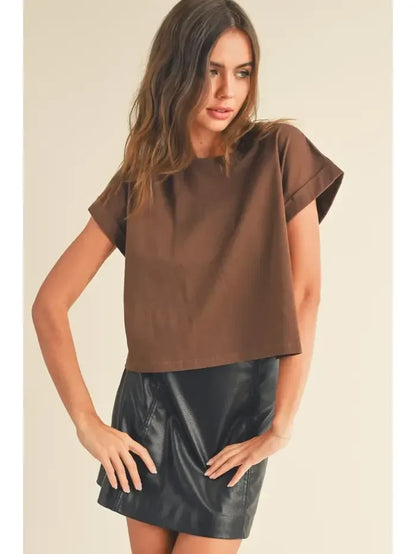 Woman wearing a round neck cuffed short-sleeved top and black faux leather mini skirt