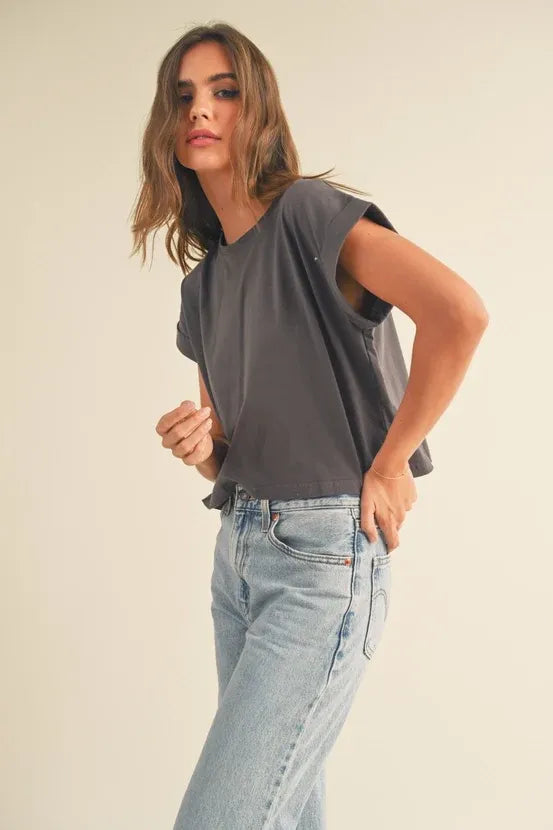 Woman wearing a dark gray round neck cuffed sleeve top with light wash blue jeans