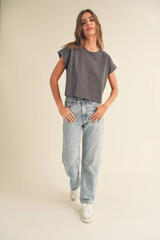 Woman wearing round neck cuffed short-sleeve top with light-wash denim jeans and white sneakers