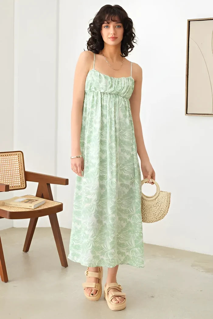 Woman in a green dress showcasing a sleeveless shirring tropical print maxi dress
